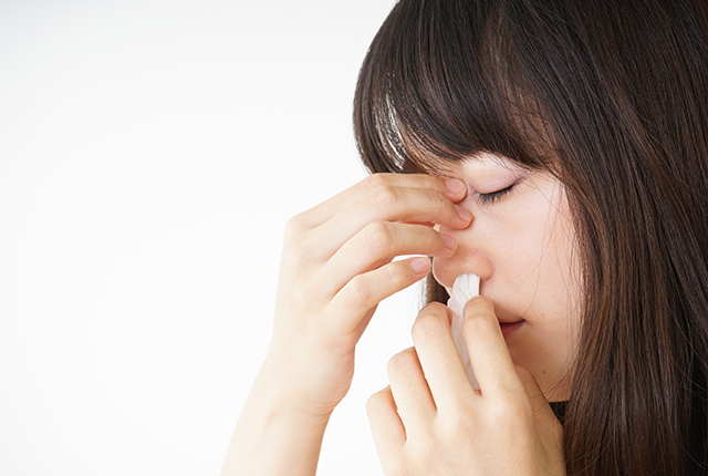 鼻をおさえる女性